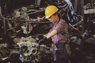 Woman engineer wearing safety gear, working on machine repair in an industrial setting.